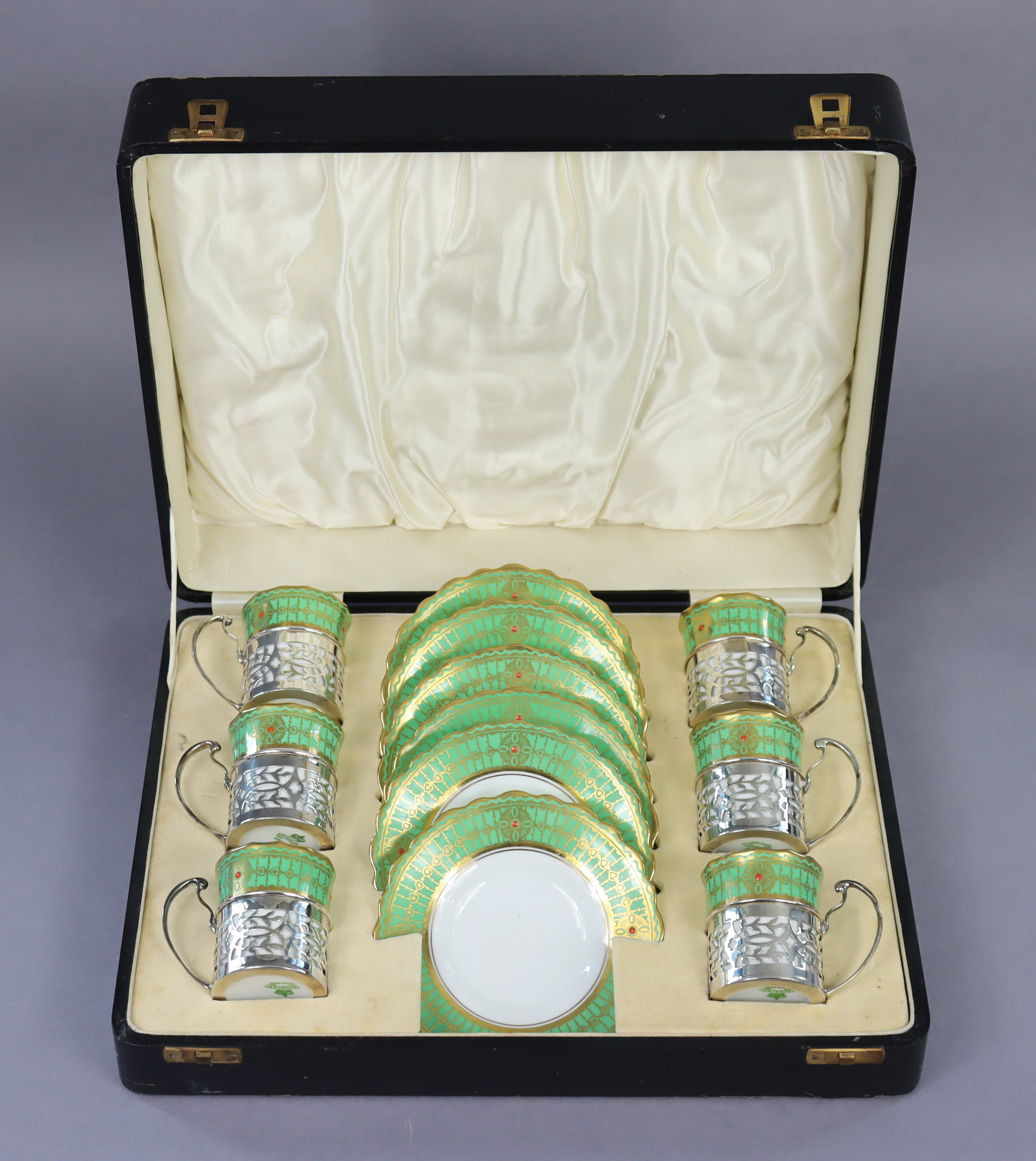 An Aynsley porcelain coffee service with green & gilt borders, the cans with pierced silver holders,