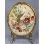 A 19th century giltwood & gesso large oval firescreen, inset petit-point needlework of a bird