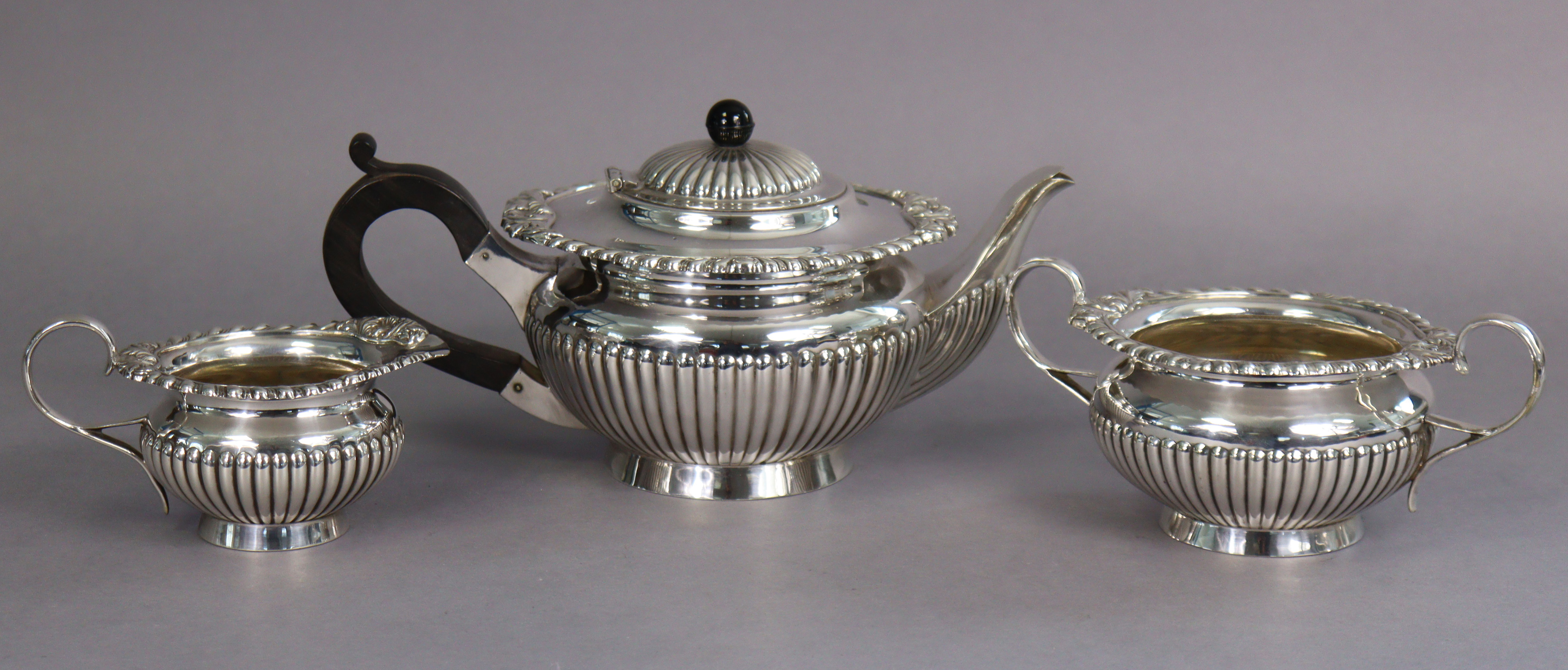 A silver-plated regency-style three-piece tea service of squat round semi-fluted form, with
