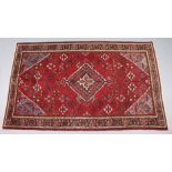 A Persian Josheghan rug of madder ground, the central medallion surrounded by floral motifs,