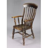 A Victorian lath-back elbow chair with a hard seat & on turned legs with spindle stretchers.