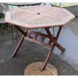 A teak octagonal garden table on shaped fold-away legs, 40” wide x 28” high; a metal patio