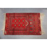 A Bokhara pattern prayer rug of madder ground, with repeating geometric designs and narrow borders,