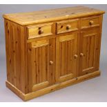 A pine sideboard fitted three frieze drawers above cupboards enclosed by three panel doors, & on a