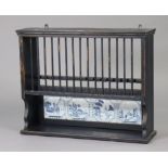 An ebonised painted wooden plate-rack inset four Delft blue & white pictorial tiles below, 29¼” wide