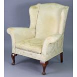 A wing-back armchair upholstered gold & ivory floral damask, & on short cabriole legs & pad feet.