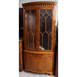 A reproduction birds-eye-maple tall bow-front standing corner cabinet having two adjustable