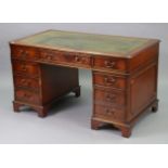 A reproduction mahogany pedestal desk inset gilt-tooled green leather, fitted with an arrangement of