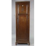 A mid-20th century oak tall hall cupboard enclosed by a panel door, & on a shaped plinth base,