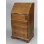 A mid-20th century small oak bureau with a fitted interior enclosed by a fall-front above four