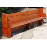 A Victorian pitch-pine long pew with a panelled back, hard seat, & on square supports, 9’4½” long