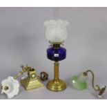 A brass oil lamp with spiral-twist column, having a blue glass reservoir, & with a frosted glass