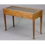 An early 20th century oak bijouterie table enclosed by a glazed hinged lift-top, & on square tapered