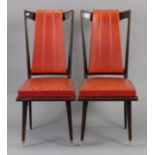 A pair of contemporary teak dining chairs each with a padded seat & back upholstered crimson