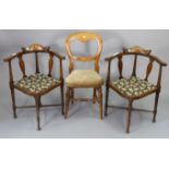 A pair of Edwardian inlaid-beech corner elbow chairs each with a padded seat, & on round tapered