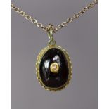 A 19th century oval garnet cabochon pendant centred by a seed pearl, in yellow metal mount, on