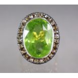 A PERIDOT AND DIAMOND RING, the large oval peridot approx. 10 carats (18 x 13 x 7mm), set within a