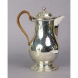 An Edwardian silver coffee pot of simple baluster shape with hinged lid & cane handle, on round