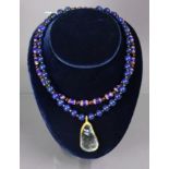 A necklace of lapis lazuli spherical beads with asymmetrical pendant of a fragment of iridescent