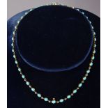 An antique gold necklace set turquoise graduated oval beads, the central portion with small rose