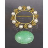 A 9ct. gold oval brooch set pale green jade within a border of cultured pearls; 2.5 cm wide. (5.5