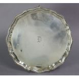 A George VII silver salver with gadrooned rim & pie-crust edge, on three scroll feet, Sheffield 1940