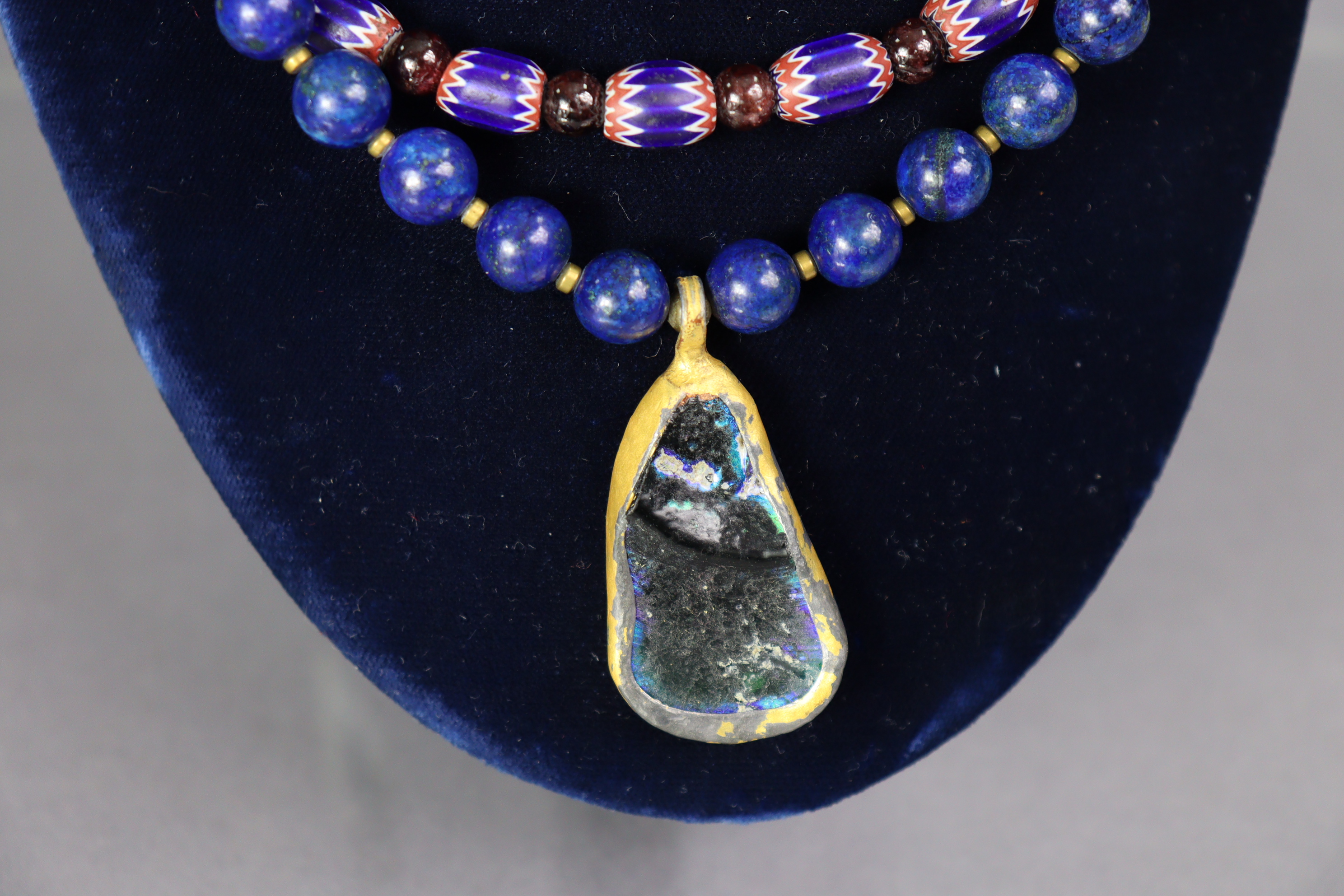 A necklace of lapis lazuli spherical beads with asymmetrical pendant of a fragment of iridescent - Image 2 of 2