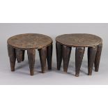 A pair of early 20th century Nupe stools, each with carved decoration to the circular seats, on nine