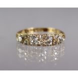 An Edwardian 18ct. gold ring set four graduated diamonds, with pairs of rose diamonds in between, to