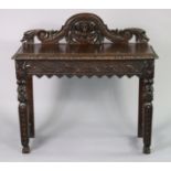 A Victorian carved oak side table with a shaped stage back, moulded edge to the rectangular top,