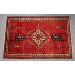 A north east Persian Meshed Baloch rug of crimson ground with a central medallion & floral motifs