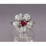 A ruby & diamond flower-head ring set centre round-cut ruby, each of the five petals set four