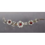 A diamond & ruby flower-spray brooch, each of the three flower heads centred by a round-cut ruby &