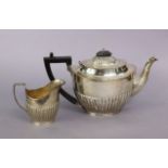 A George V silver teapot of oval form with ebonised angular handle and fluted decoration (20oz all-