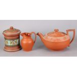 A 19th century Wedgwood terracotta teapot, 9½” long x 5” high; a ditto jug, 4¾”; & a similar