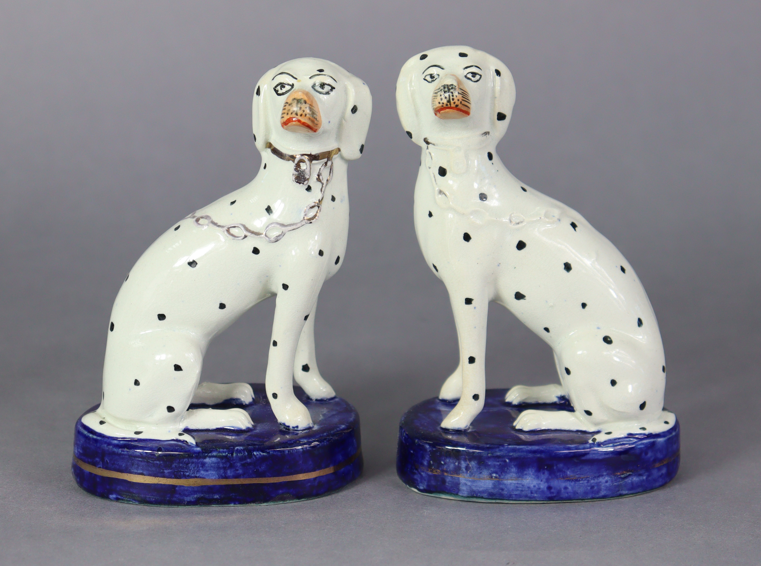 A pair of 19th century Staffordshire pottery models of spaniels, each seated on blue oval base