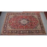 A central Persian Kashan carpet of madder found, featuring a central medallion surround by flower-