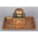 An Arts & Crafts copper inkwell with planished surface & embossed roundels to the square central