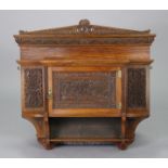A Victorian mahogany wall cabinet, with carved ferns & insects to the panel doors enclosing a centr