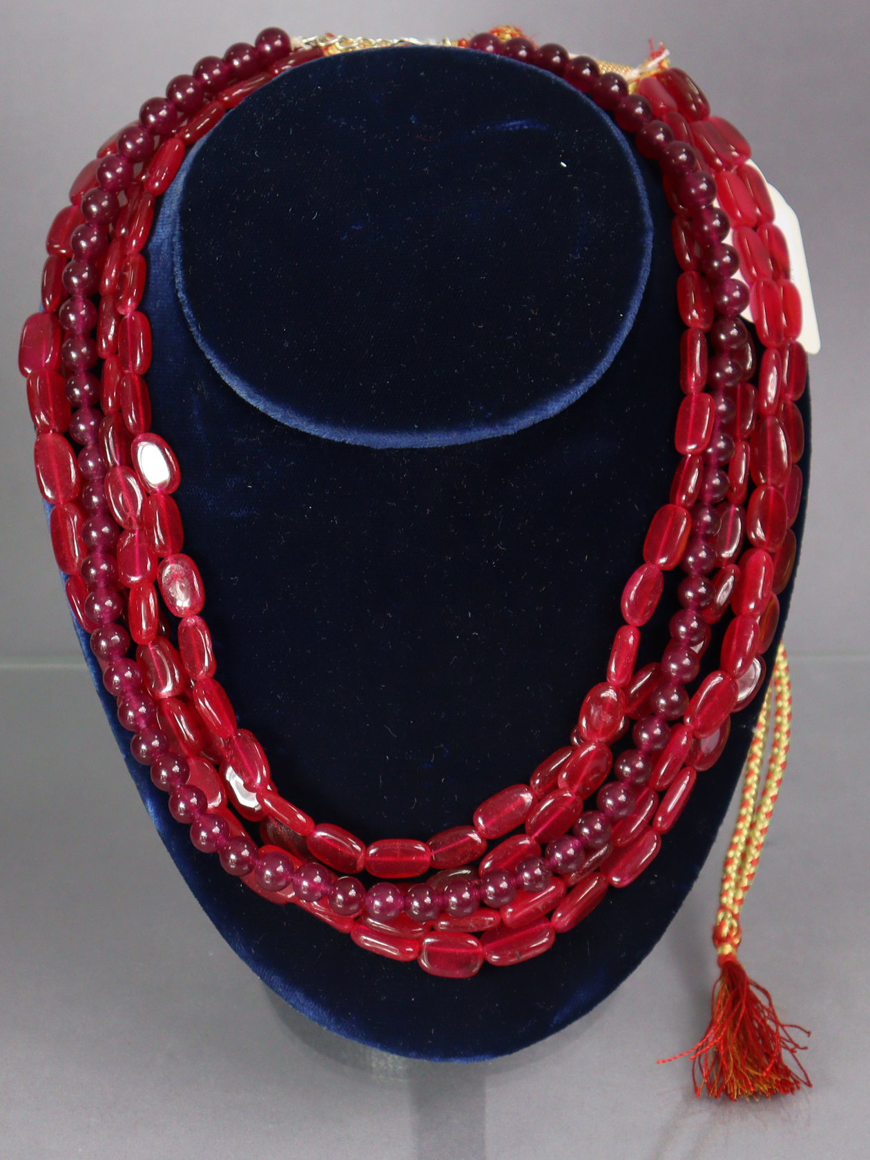 A three-strand necklace of red crystal-quartz oval beads, with woven gold & red silk cord; & a