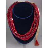 A three-strand necklace of red crystal-quartz oval beads, with woven gold & red silk cord; & a