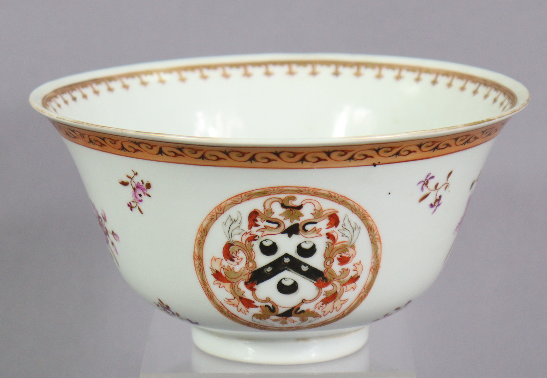 An 18th century Chinese export porcelain bowl with painted armorials in reserves, & floral sprays