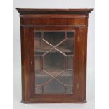 A Georgian mahogany hanging corner cabinet with moulded cornice above two shelves enclosed by an