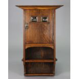 An early 20th century arts & crafts oak wall cabinet with a moulded cornice above two shelves,