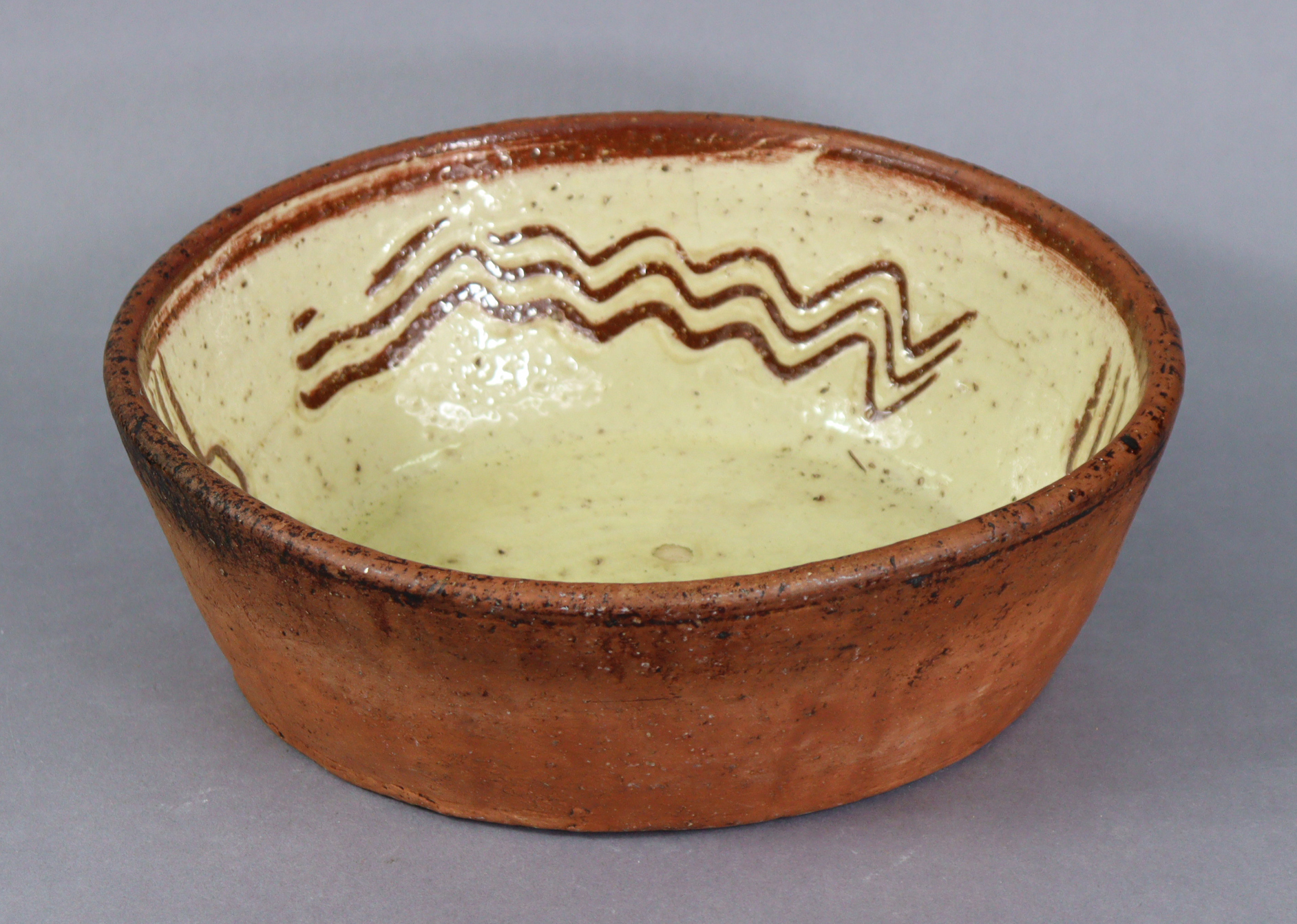 A 19th century English slipware oval baking dish, the cream-glazed interior with sgraffito