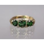 A 9ct gold ring set three graduated green stones with pairs of tiny diamonds in between; size: K;