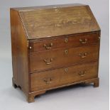 A Georgian oak bureau with a fitted interior enclosed by a fall-front above three long graduated