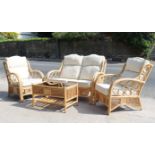 A rattan four-piece conservatory suite comprising of a two-seater settee with loose cushions to