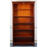 A reproduction mahogany tall standing open bookcase with five adjustable shelves, & on a shaped