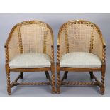 A pair of 1930s oak tub-shaped chairs each with a woven-cane back, padded seat, & on barley-twist